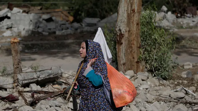 A Palestinian woman walks while raising a white flag in the Gaza Strip